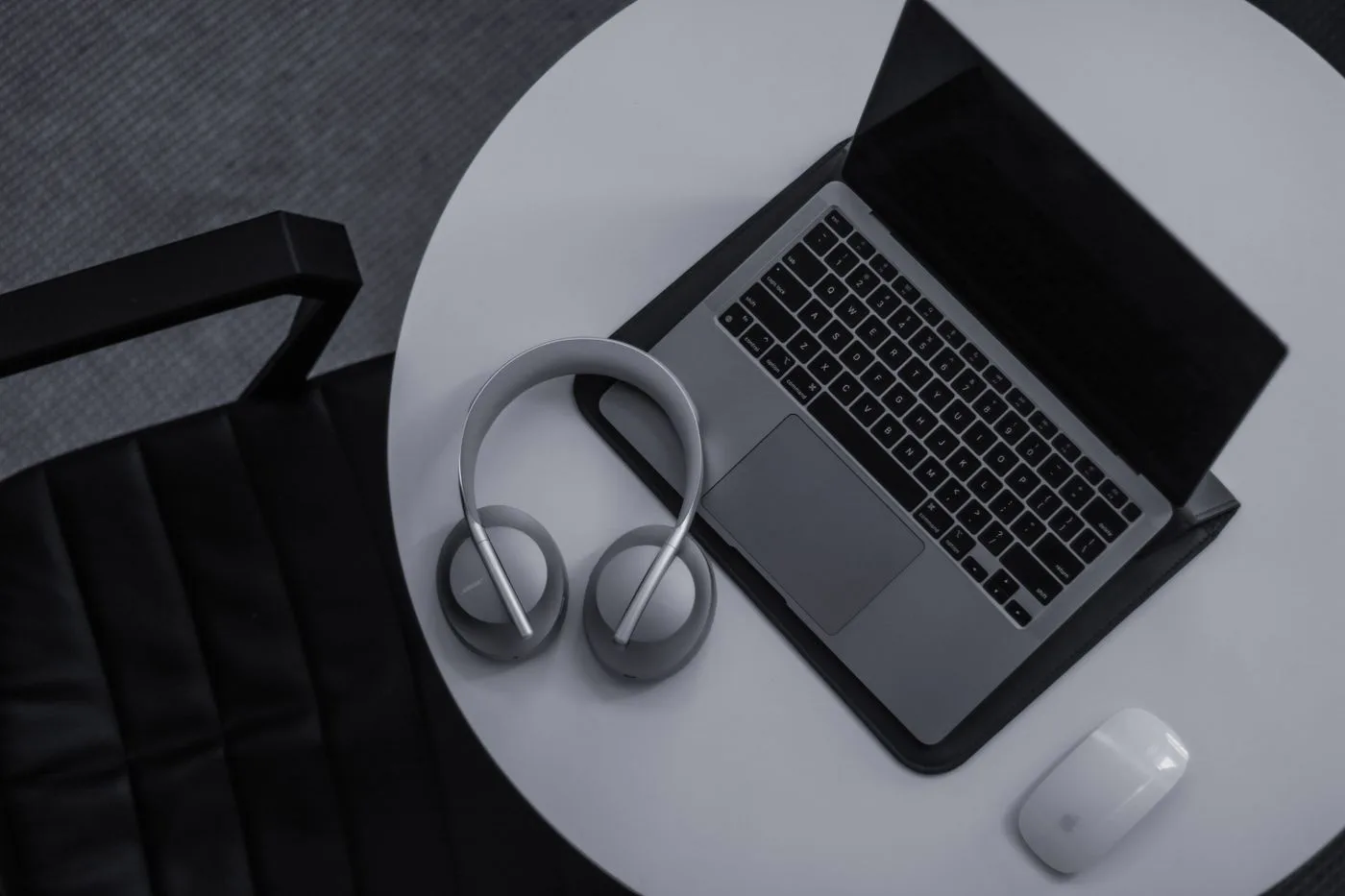 Laptop, headphones, and mouse arranged on a workspace table
